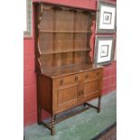 A light oak dresser, shaped uprights to top, two short drawers over two door cupboard to base,