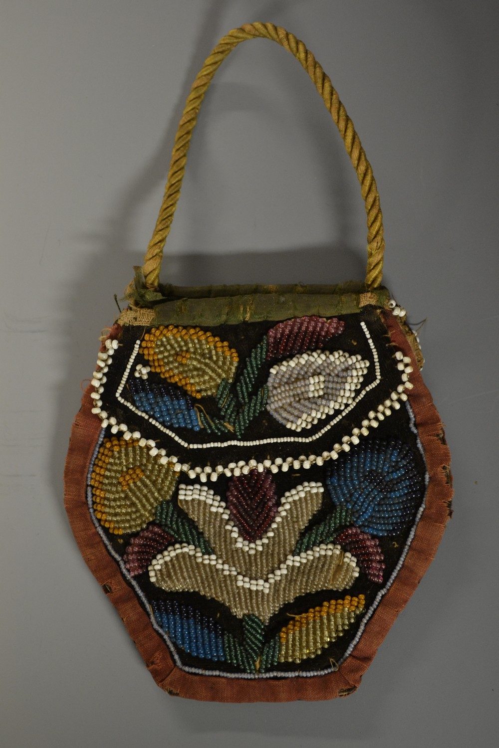A 19th century beadwork purse, colourfully worked with stylised flowers, rope twist handle,