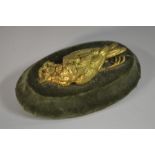 A 19th century desk weight, cast with a gilded dead song bird, on an oval green velvet base,