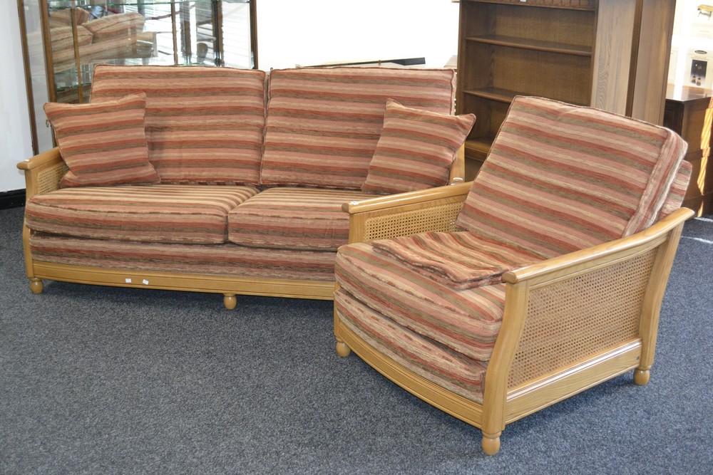 An Ercol Bergere range 16032FLT light oak two seat sofa with canework ends; a conforming armchair.