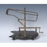 A French brass and ebonised mechanical pouring wine cradle, screw-thread mechanism, shaped base,