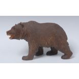 A Black Forest carving, of a bear, on all fours, painted features, 17cm long,