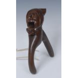 A Black Forest lever action novelty nut cracker, carved as the head of a gentleman in a cloth cap,