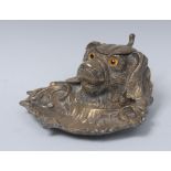 A 19th century brass novelty inkwell, cast as the head of a dog, hinged cover, glass eyes,