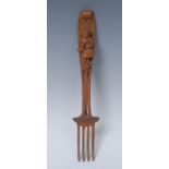 A Black Forest fork, the handle carved in relief with a young girl stirring a pan, 25.