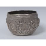 A Burmese silver circular bowl, typically repousse chased with deities on a textured ground,