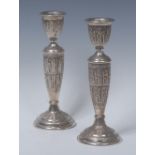 A pair of Persian silver candlesticks, chased with rows of figures in the Assyrian manner,