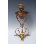 An Arts and Craft copper and brass oil lamp, the copper reservoir supports on sinuous brass frame,