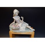 A Lladro figure of a young girl, seated with flower basket, 22cm in length,