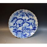 A Japanese shaped circular plate, painted in underglaze blue with flowering peonies, 30cm diam,