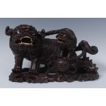 A Chinese hardwood carving, of a Dog of Fo, another, on its back, mouths open with teeth bared,