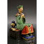 A Studio Pottery figure by Reg Johnson, Mandarin, seated in quiet repose with hands folded,