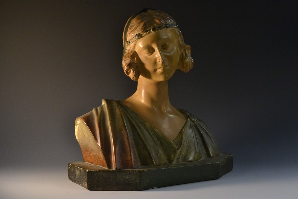 An Art Nouveau French plaster bust, head and shoulders, of a lady, wearing a head piece,