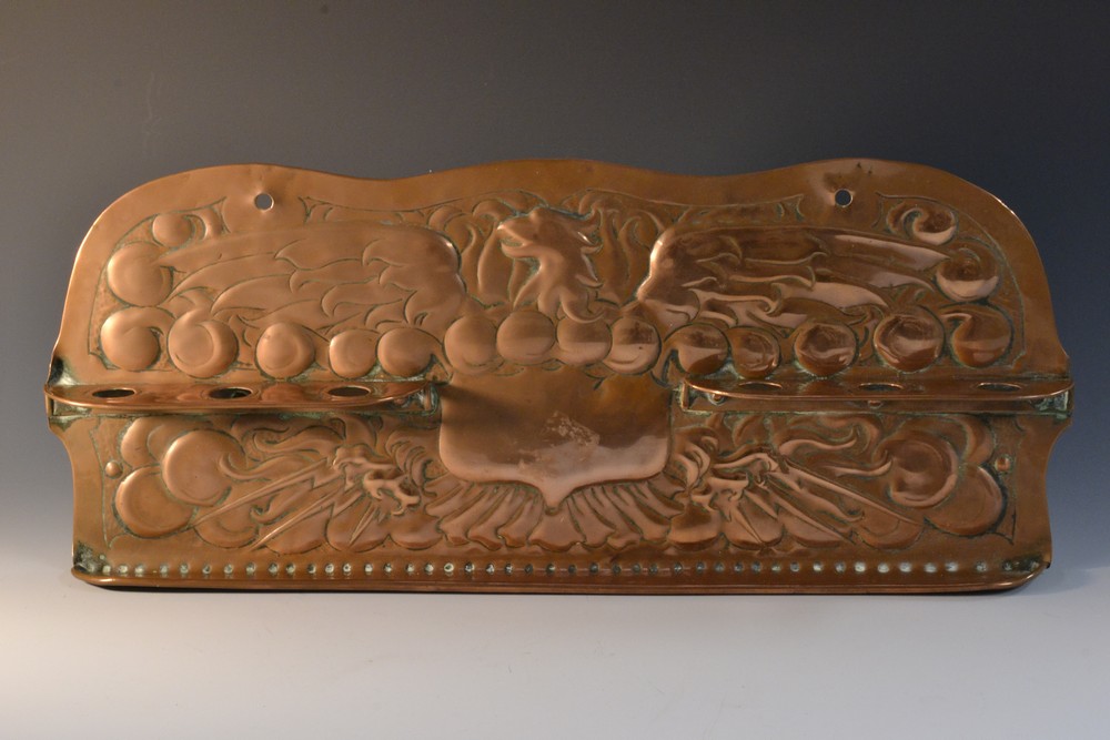 An Arts and Crafts copper pipe rack, embossed with phoenix, 43cm wide, c.