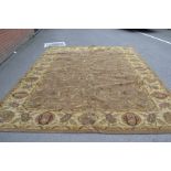 A large Indian hand tufted woolen carpet floral designs on a cafe - au - lait ground, brown border.