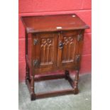 An oak Priory style two door cabinet, rectangular top, two doors, turned legs.