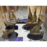 A silver coloured metal model of a Chinese ship, 16cm long, oval ebonised base; another,