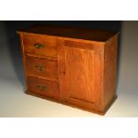 A late Victorian oak table cabinet, oversailing top above three drawers flanked by a panelled door,