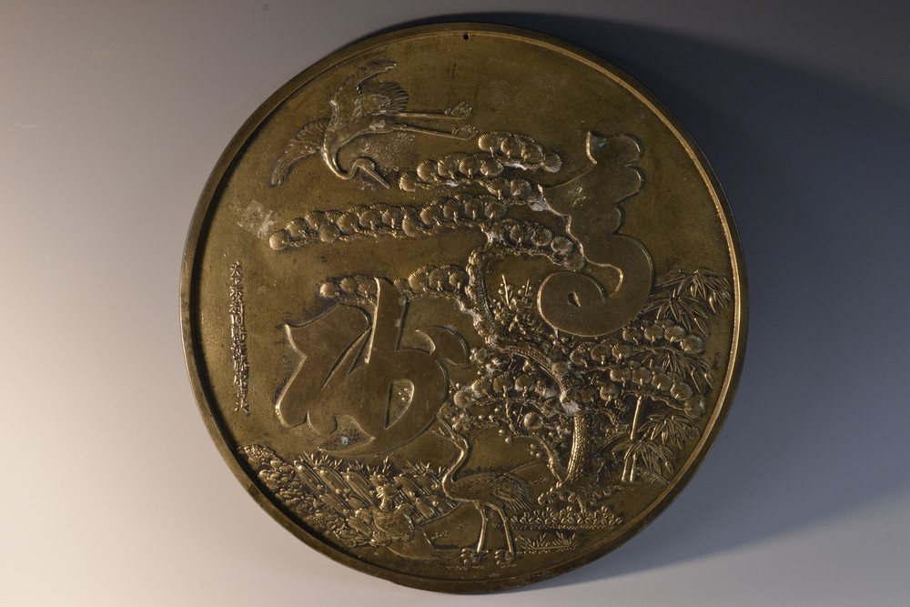 A Chinese bronze circular mirror, in relief to verso with the Three Friends of Winter,