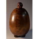 A Continental beech novelty tobacco jar, the cover with the head of a monk emerging from a barrel,