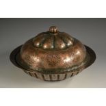 A 19th century Islamic fluted circular copper banquet dish and cover, chased with figures,