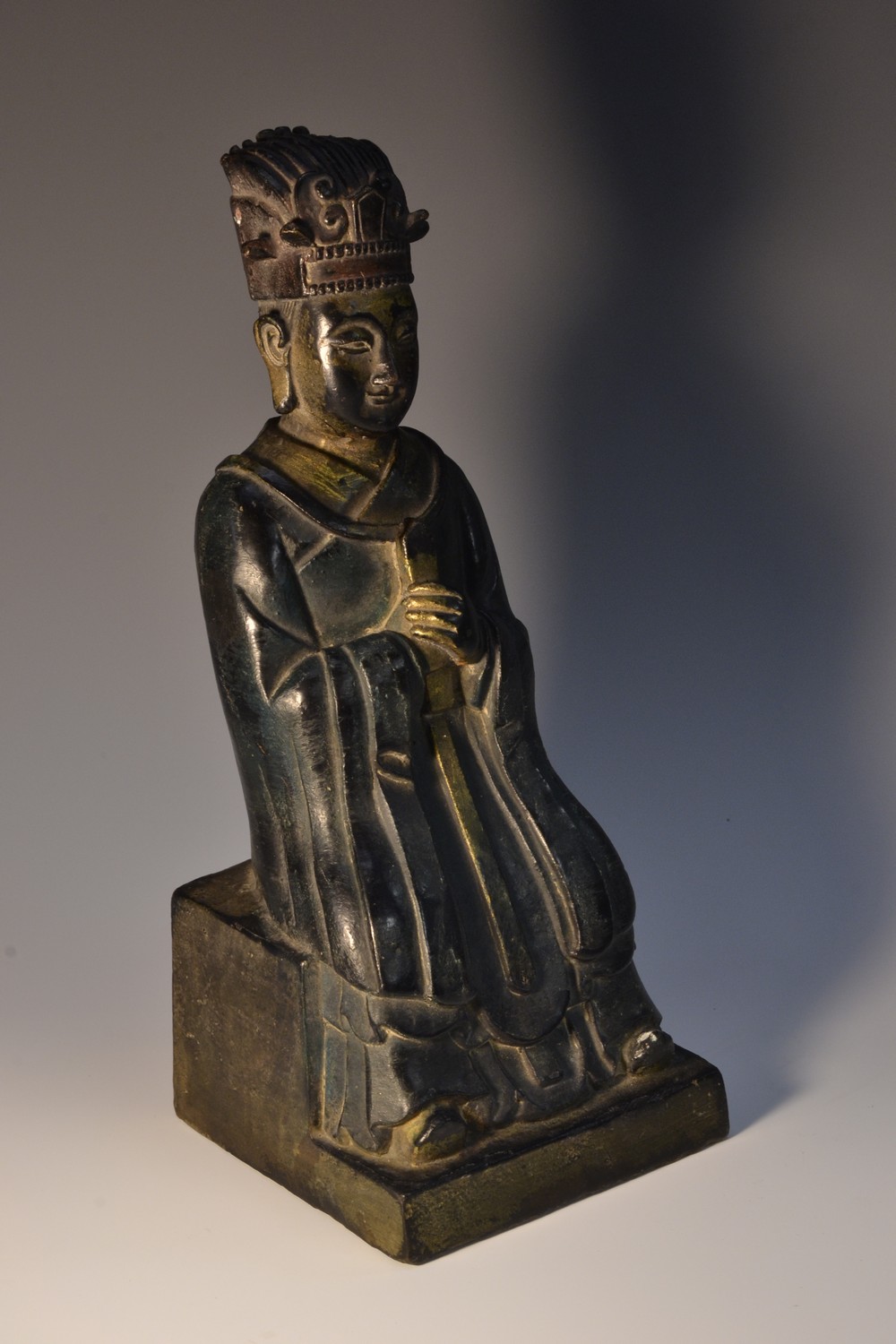 A Chinese gilt and polychrome painted bronze figure, of an elder, seated holding a sceptre,