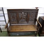 An oak hall settle, carved panel back depicting master and servants,