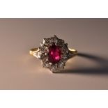 A diamond and ruby cluster ring, central oval red ruby 1.0ct, measuring 7.0 x 5.0 x 2.