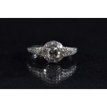 A diamond ring, principle round brilliant cut diamond surrounded by a banded of conforming accents,