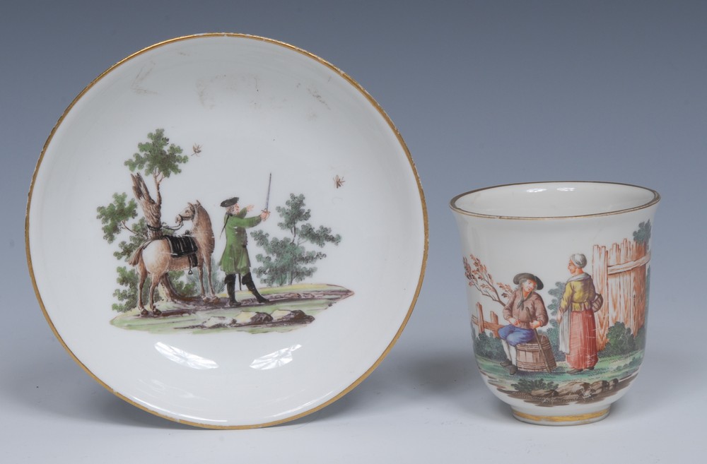 A Meissen coffee cup and saucer, painted with landscapes, with figures, gilt line rims,