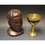 A coconut husk and brass mounted goblet; a carved bust of a tribesman, signed R. P.