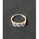 A diamond and tanzanite ring, set with three oval pale blue/purple tanzanite's,