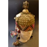 An Afghani wedding helmet, woven fabric and metal body, suspending beaded and bell mounted droplets,