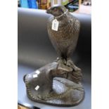 A bronzed resin model of a bird of prey perched on a gauntlet,