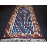 A hand woven Persian Zealous rug, geometric designs in hues of red, blue, cream and brown.