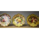 A set of three Coalport shaped circular cabinet plates, painted with ripe fruit, signed, M Cooke,