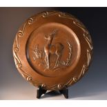 An Art Deco circular plainished copper plaque, the dished central field embossed with an ibex,