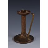 An Arts and Crafts copper chamberstick, plainished throughout, the drip tray,