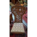 An Anglo-Indian hardwood nursing chair, floral cresting top rail, fretworked and carved back,