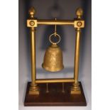 A brass dinner gong, as a bell, suspended within an architectural frame, rectangular mahogany base,