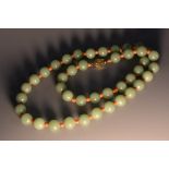 A Chinse jade necklace, the forty-two spherical beads divided by coral spaces, silver-gilt clasp,