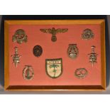 An arrangement of German badges, Afrika Corp cloth badge, others, framed, 23.5cm x 34.