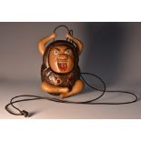 A Japanese hardwood tonkotsu or tobacco box, carved in the Kobi manner, as a grotesque figure,