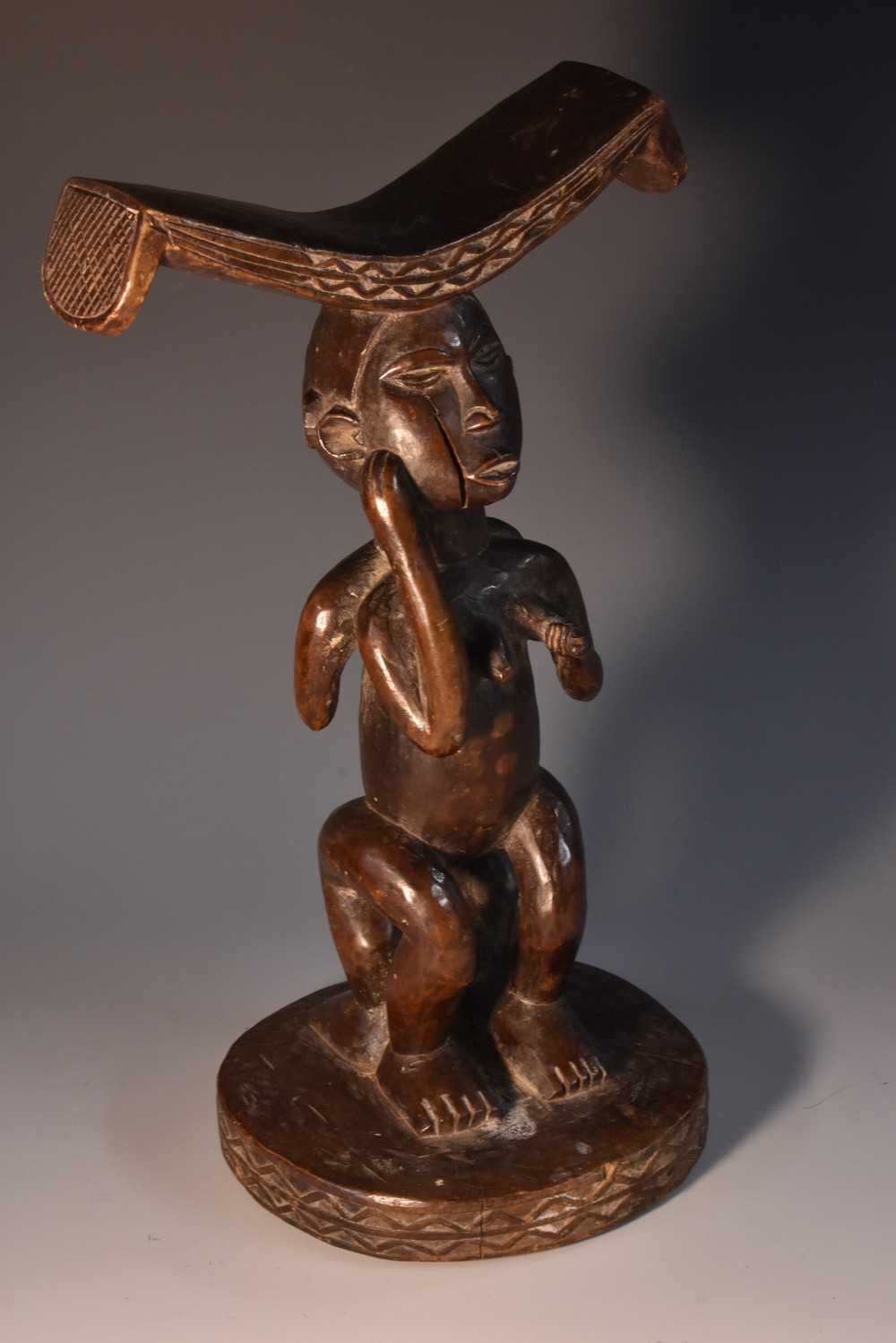 Tribal Art - an African figural headrest, the curved cresting with chequered ends,