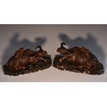 A pair of Chinese hardwood carvings, of boys on buffalo, pierced stands, 25cm wide, c.