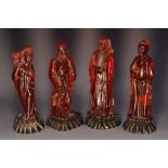 A set of four Chinese faux cherry amber figures, of immortals, each stands, holding an attribute,