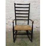 A rush seated ladder back rocking armchair, ebonised black ash?