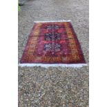 .A late 20th century Afghan Kanduz rug with three central medallions on red ground with a