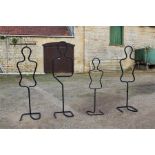 Four freestanding metal clothes tube mannequins.