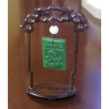 Spinach green jade toggle on carved timber stand decorated with a snake, 17cm high